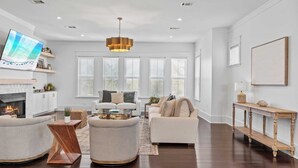 A spacious living room with a fireplace, two sofas, a coffee table, and a TV mounted on the wall. - 2 Homes, Sleeps 25 Pool, Firepit, Free Golf Carts Blue Mountain Beach (Santa Rosa Beach)