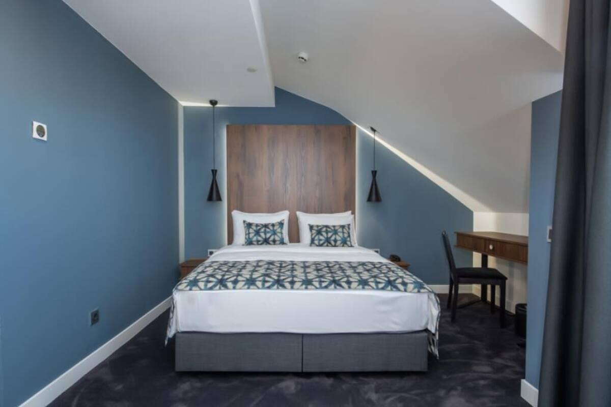 A bedroom with a bed, bedside tables, a desk, and a chair.
