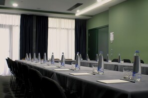 A conference room with a long table, chairs, water bottles, and a green wall. - Hotel Twenties Tbilisi - Stay & Dine (Tbilisi)