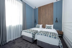 A hotel room with two beds, a wooden accent wall, and a window with curtains. - Hotel Twenties Tbilisi - Stay & Dine (Tbilisi)