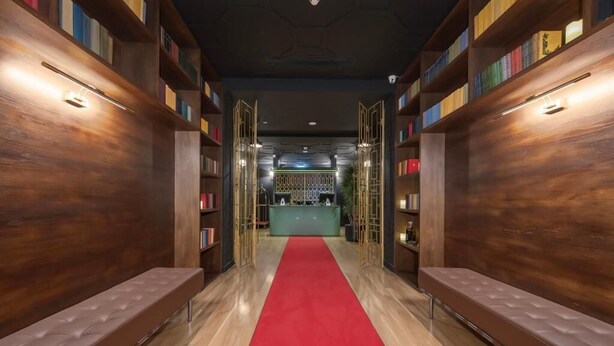A hallway with wooden bookshelves, a red carpet, and a reception desk. - Hotel Twenties Tbilisi - Stay & Dine (Tbilisi)