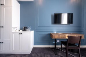 A modern kitchen with white cabinets, a wooden table, and a mounted TV. - Hotel Twenties Tbilisi - Stay & Dine (Tbilisi)