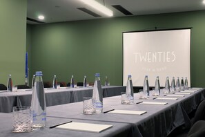 A conference room with tables set for a meeting, water bottles, and a screen displaying "TWENTIES Stay & Dine". - Hotel Twenties Tbilisi - Stay & Dine (Tbilisi)