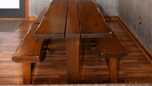 Um quarto com painéis de madeira, uma mesa grande de madeira e bancos.