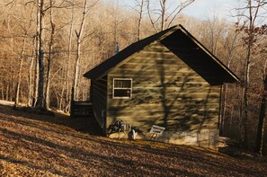 A small cabin with a window and a sign indicating it is a treestand cabin. - Treestand Cabin at Gap Creek Cabins (Scott County)