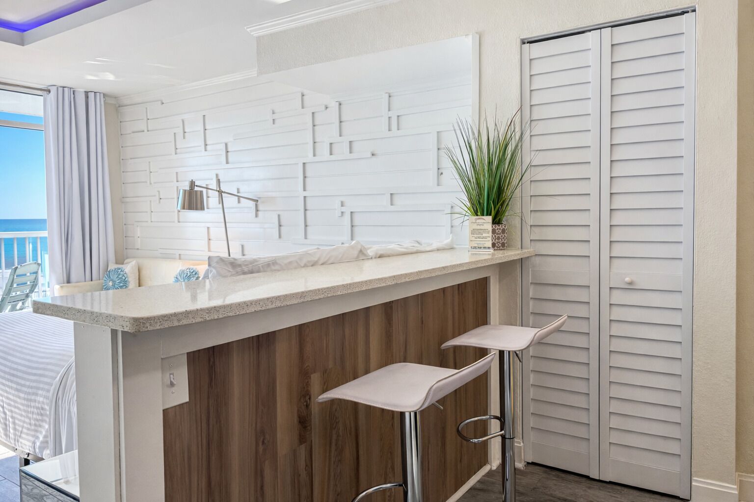 A modern kitchen with a white backsplash, wooden paneling, and two bar stools.