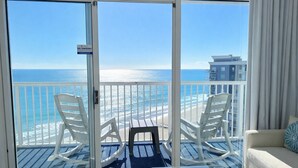 A balcony with a 'NO SMOKING' sign, white chairs, a small table, and a view of the ocean and buildings. - Modern Oceanfront Couple Retreat, SeaWatch 1703 NT (Myrtle Beach)