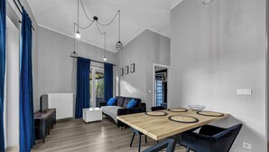Een moderne woonkamer met een houten eettafel, blauwe gordijnen en een bank met kussens.