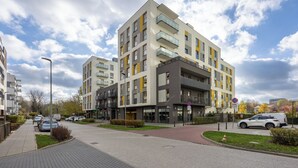 Een modern appartementencomplex met meerdere balkons, een poort en een verharde oprit.