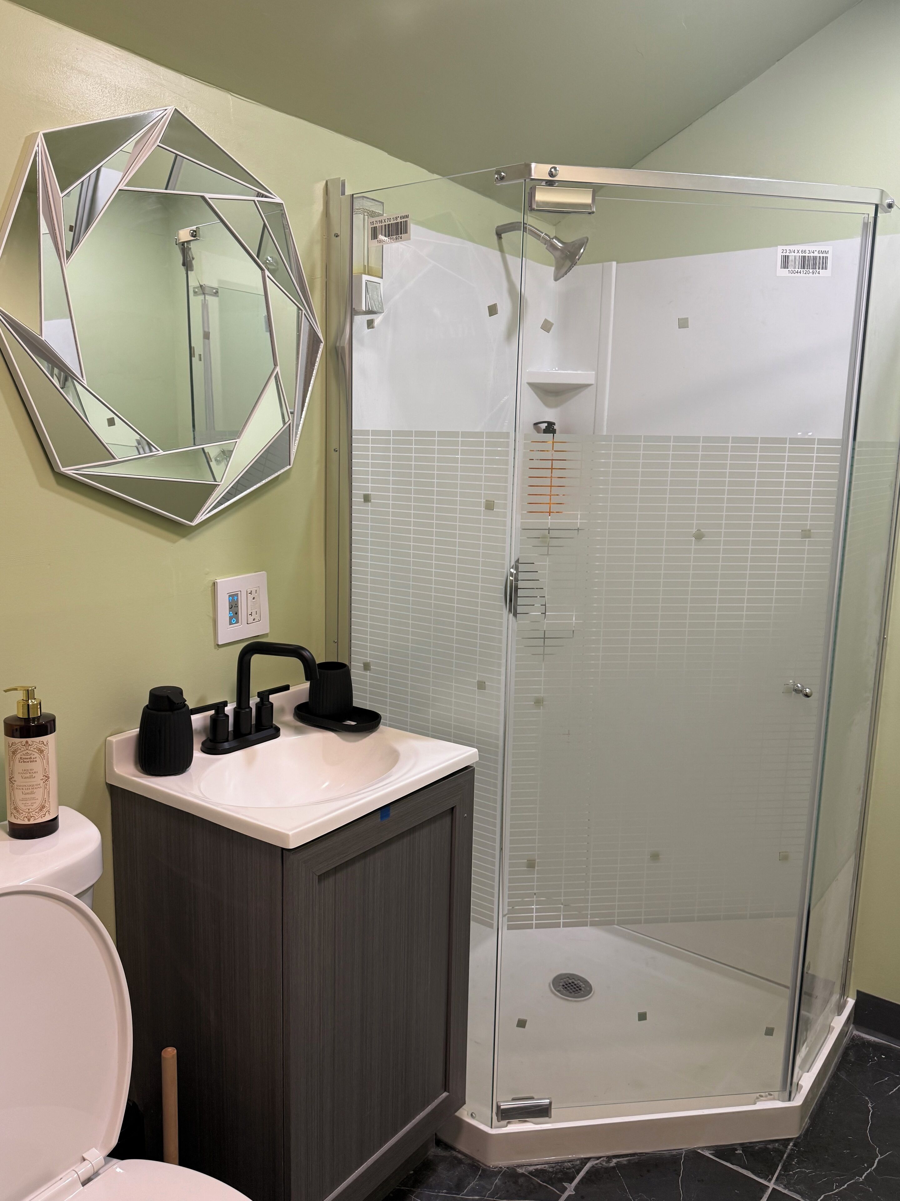 A bathroom with a glass-enclosed shower, a white sink, and a large mirror.