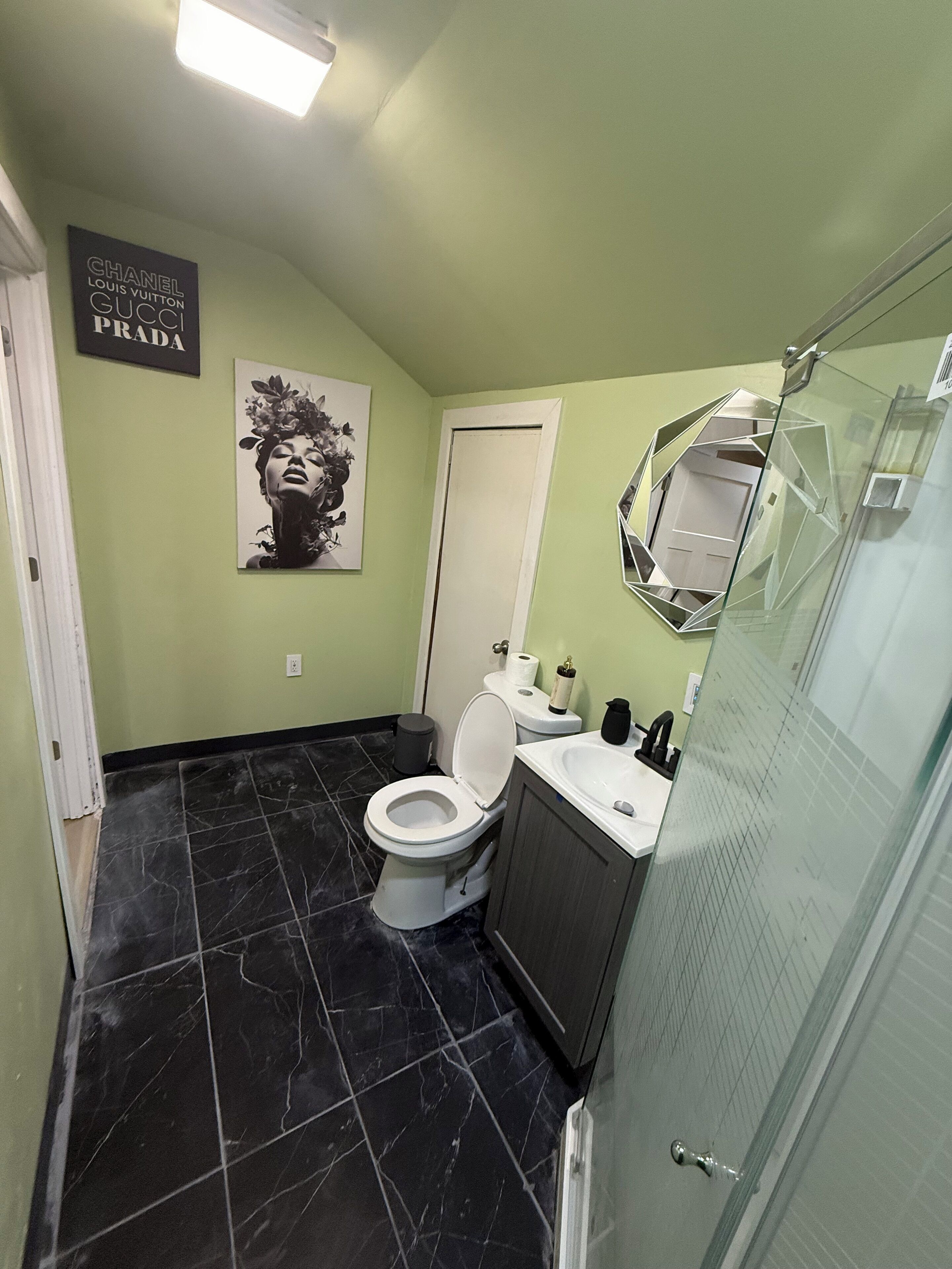 A bathroom with a toilet, sink, and glass shower enclosure.