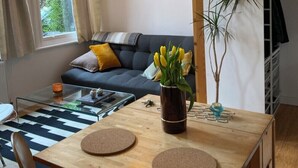Ett mysigt vardagsrum med en soffa, ett soffbord, ett matbord och en hängande lampa.