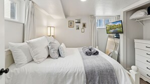 A neatly arranged bedroom with a bed, a television, and a dresser. - Family Retreat Near Trails & Downtown • BBQ, Fire Pit & Kids’ Games (Ogden)
