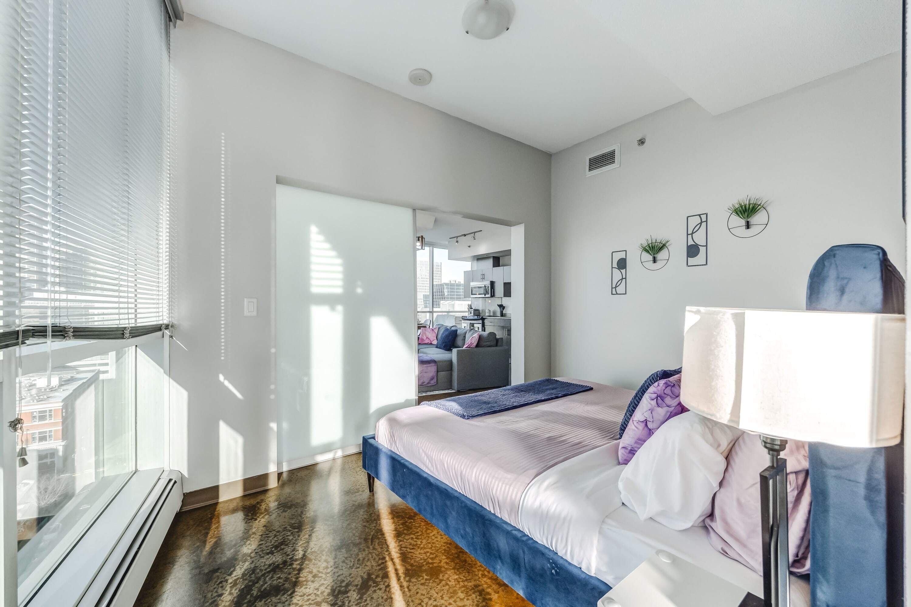 Un dormitorio moderno con cama, lámpara y vistas a la ciudad.