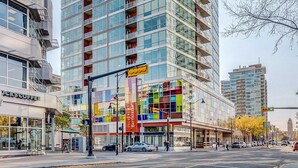 Un immeuble moderne de grande hauteur, doté d’une façade en verre, de nombreux balcons et d’une partie rouge bien visible sur le dessus.