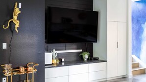 A modern living room with a flat-screen TV mounted on a black wall, a gold monkey sculpture, a glass coffee table, and a white cabinet. - Electric Disco Oasis Near Rainey, UT and Top Spots (Austin)
