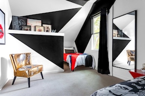 A modern bedroom with a sloped ceiling, a bed with a red and white bedspread, a gold-framed armchair, and a large mirror on the wall. - Electric Disco Oasis Near Rainey, UT and Top Spots (Austin)