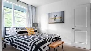 A modern bedroom with a large bed, a bench, a window with curtains, and a door. - Electric Disco Oasis Near Rainey, UT and Top Spots (Austin)