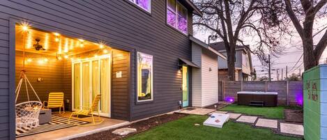 A modern house with a patio area featuring outdoor seating and a hot tub.