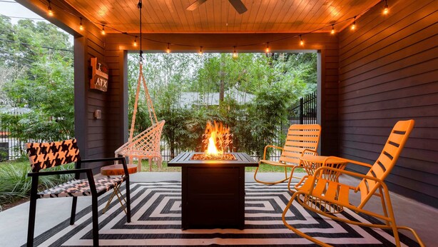 An outdoor patio with a fire feature, seating, and a view of greenery. - Electric Disco Oasis Near Rainey, UT and Top Spots (Austin)