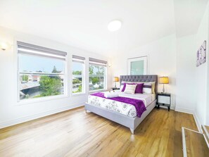 A bedroom with a bed, two bedside tables, a window with a view, and a ceiling light.