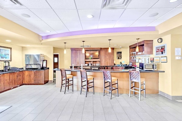A bar area with a counter, bar stools, a television, and kitchen appliances. - Two Queen Bed Suite w Pool, Hot Tub Near Disney (Orlando)
