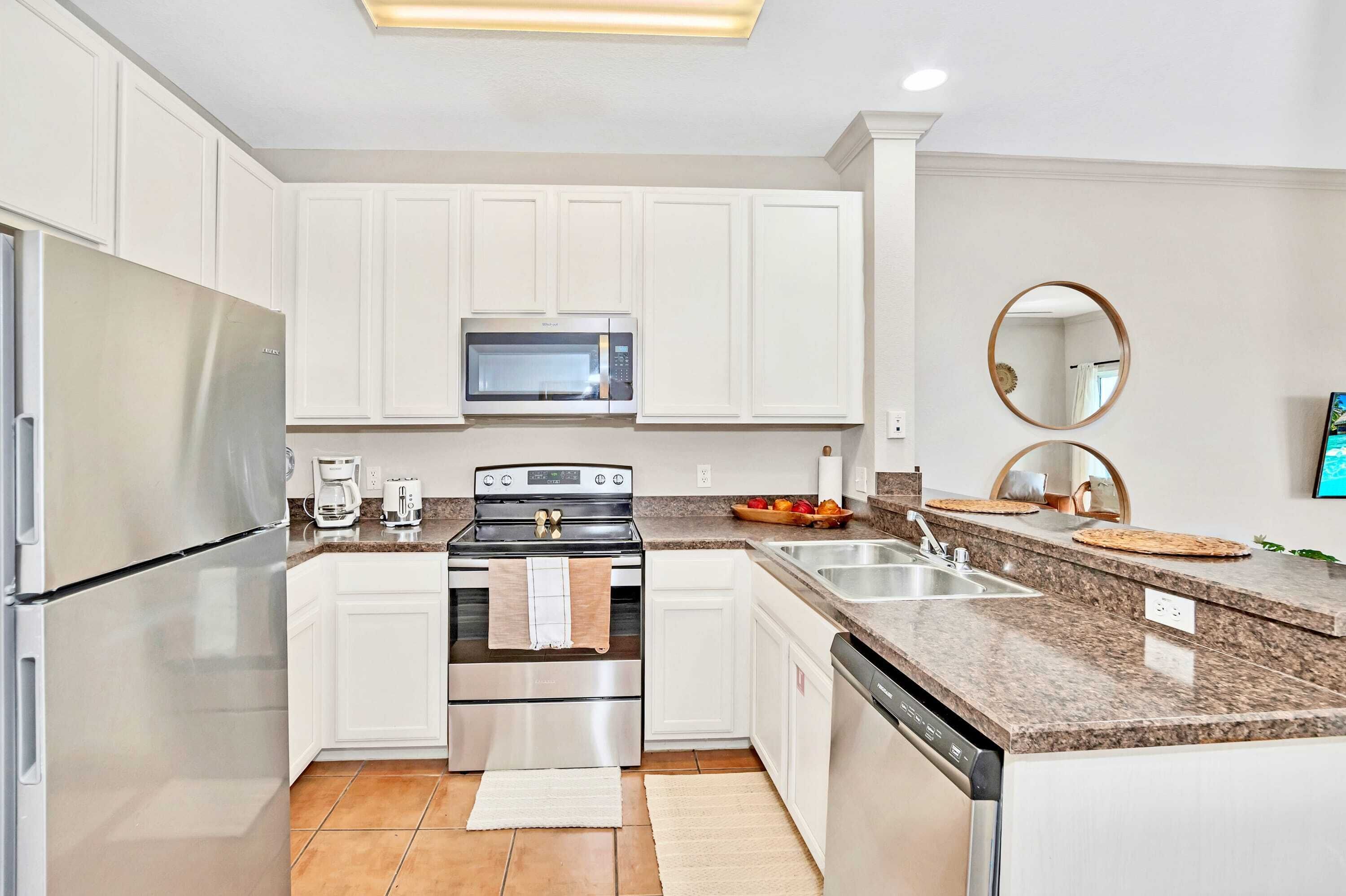 A modern kitchen with white cabinets, stainless steel appliances, granite countertops, and a built-in oven.