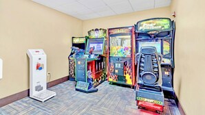 A row of arcade machines in a hallway with a scale and a water dispenser. - Condo 1BR Near Disney- Pool and Hot Tub! (Orlando)