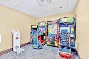 A row of arcade machines in a hallway with a scale and a water dispenser. - Condo 1BR Near Disney- Pool and Hot Tub! (Orlando)