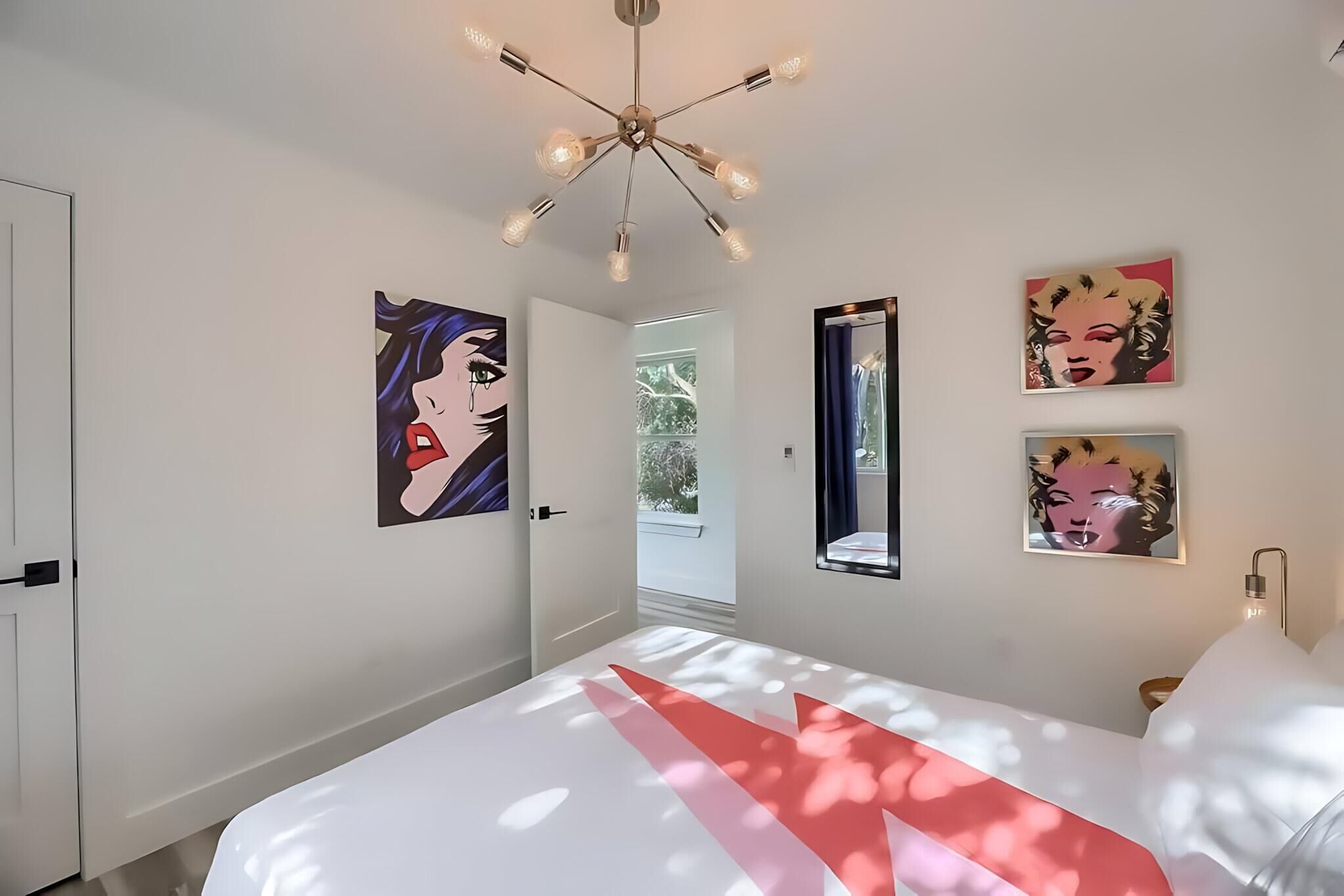 A modern bedroom with a bed, a ceiling light fixture, and wall art.