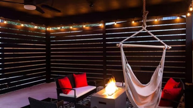A cozy outdoor seating area with a hammock, a fire pit, and string lights. - Stylish 3BR East Side Retreat w Patio & BBQ (Austin)