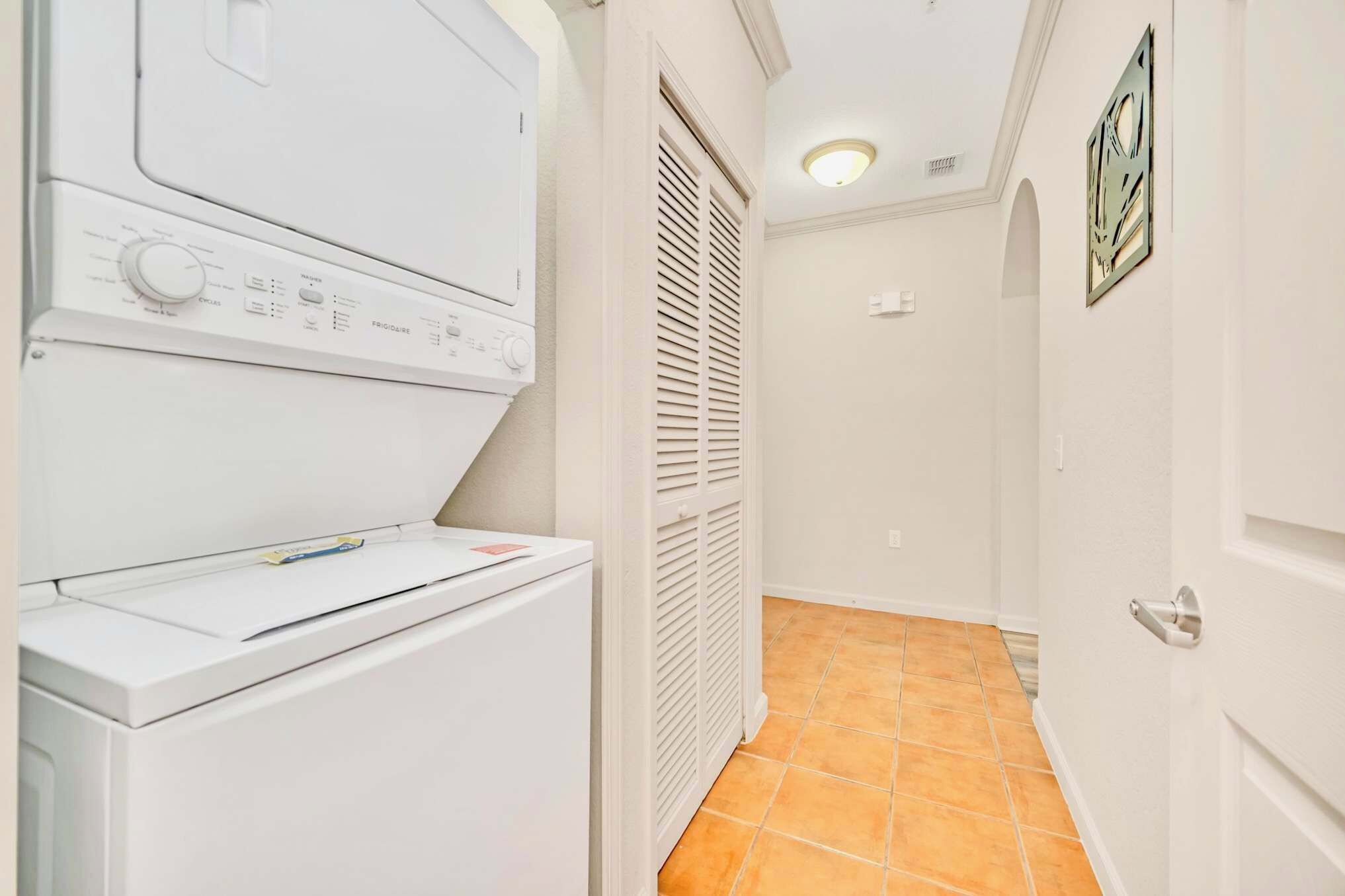 A laundry room with a front-loading washer and dryer, a vented dryer, and a tiled floor.
