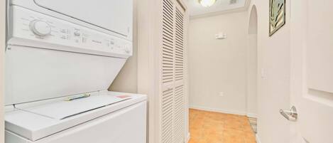 A laundry room with a front-loading washer and dryer, a vented dryer, and a tiled floor.