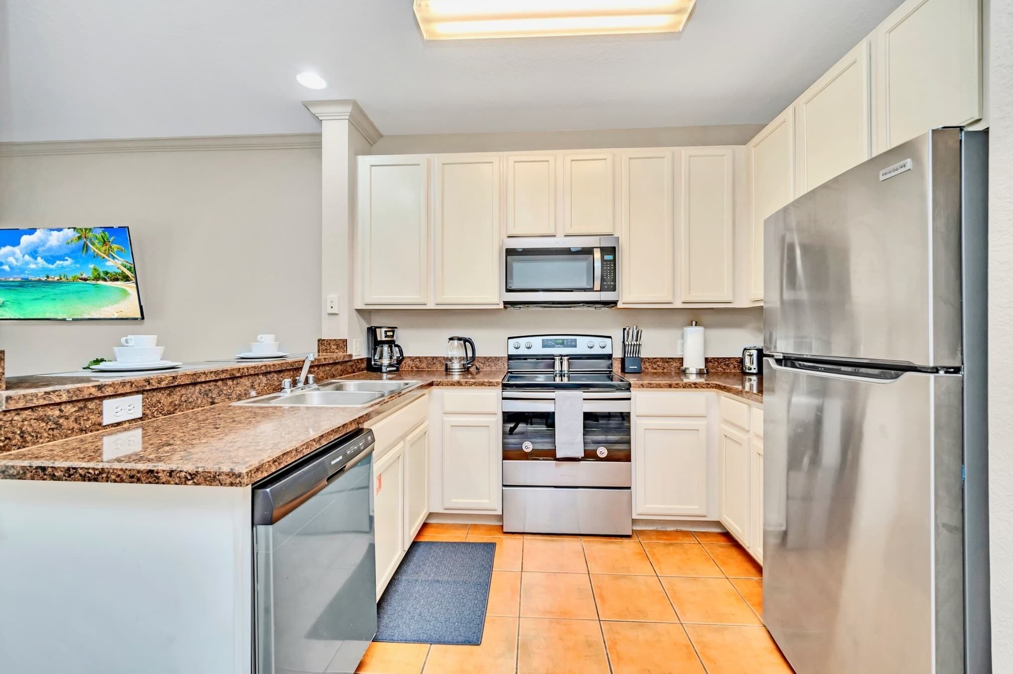 A modern kitchen with white cabinets, stainless steel appliances, a granite countertop, and a large window.