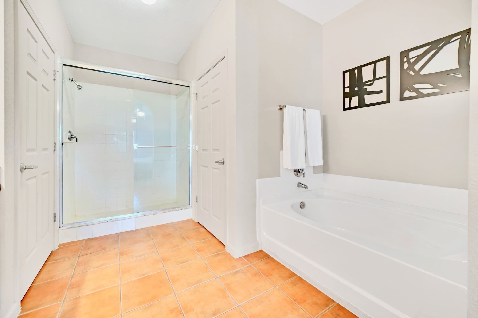 Un bagno con box doccia in vetro, una vasca da bagno bianca e pavimento piastrellato.