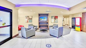 Eine Lobby mit Sitzgelegenheiten, einem Fernseher und einem Fahrkartenschalter.