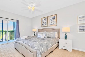 A bedroom with a bed, two bedside tables, a ceiling fan, and artwork on the walls. - Upstay - Condo w Pool and More - Near Disney (Winter Garden)