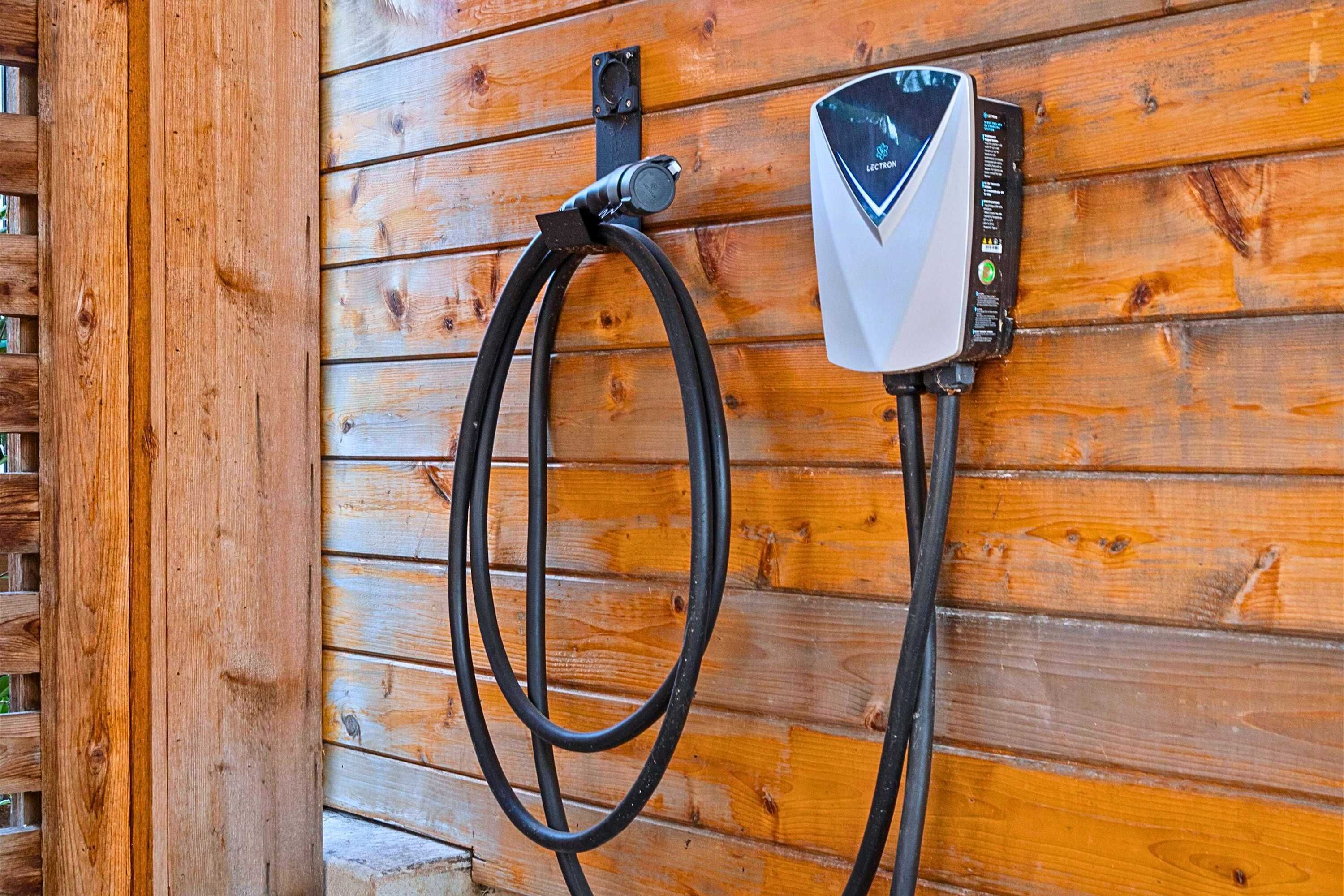 A wall-mounted electric vehicle charging station with a cable connected to it.
