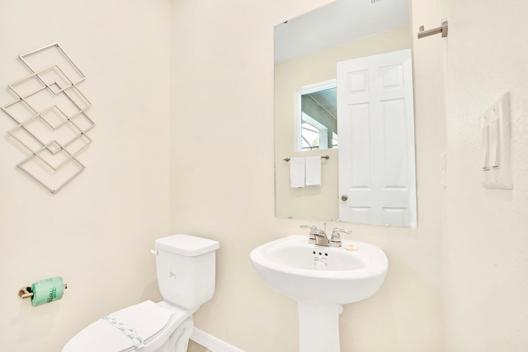 Une salle de bain équipée de toilettes, d’un lavabo, d’un miroir et d’un porte-serviettes.