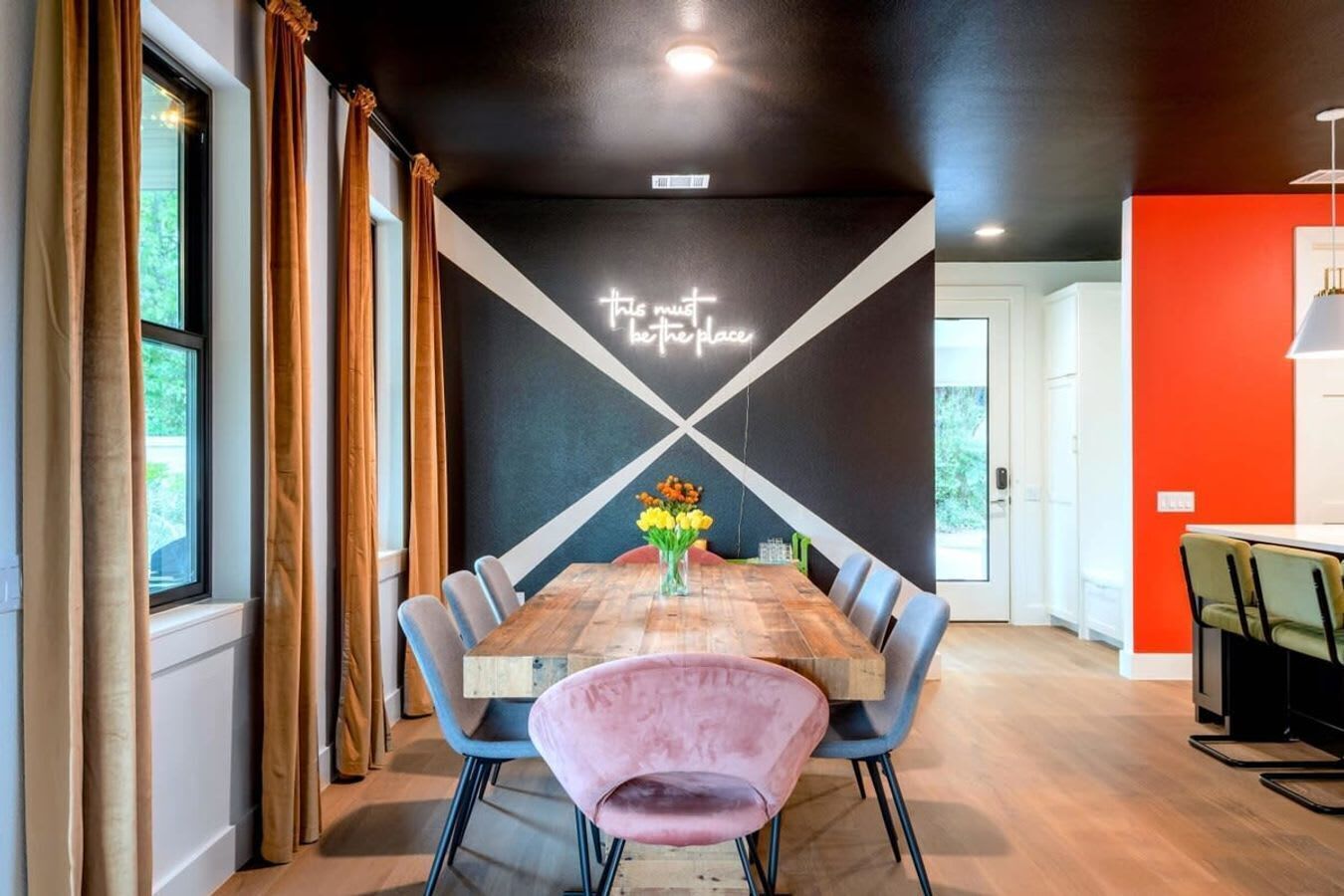 Un comedor con una mesa de madera, sillas azules y un jarrón con flores.