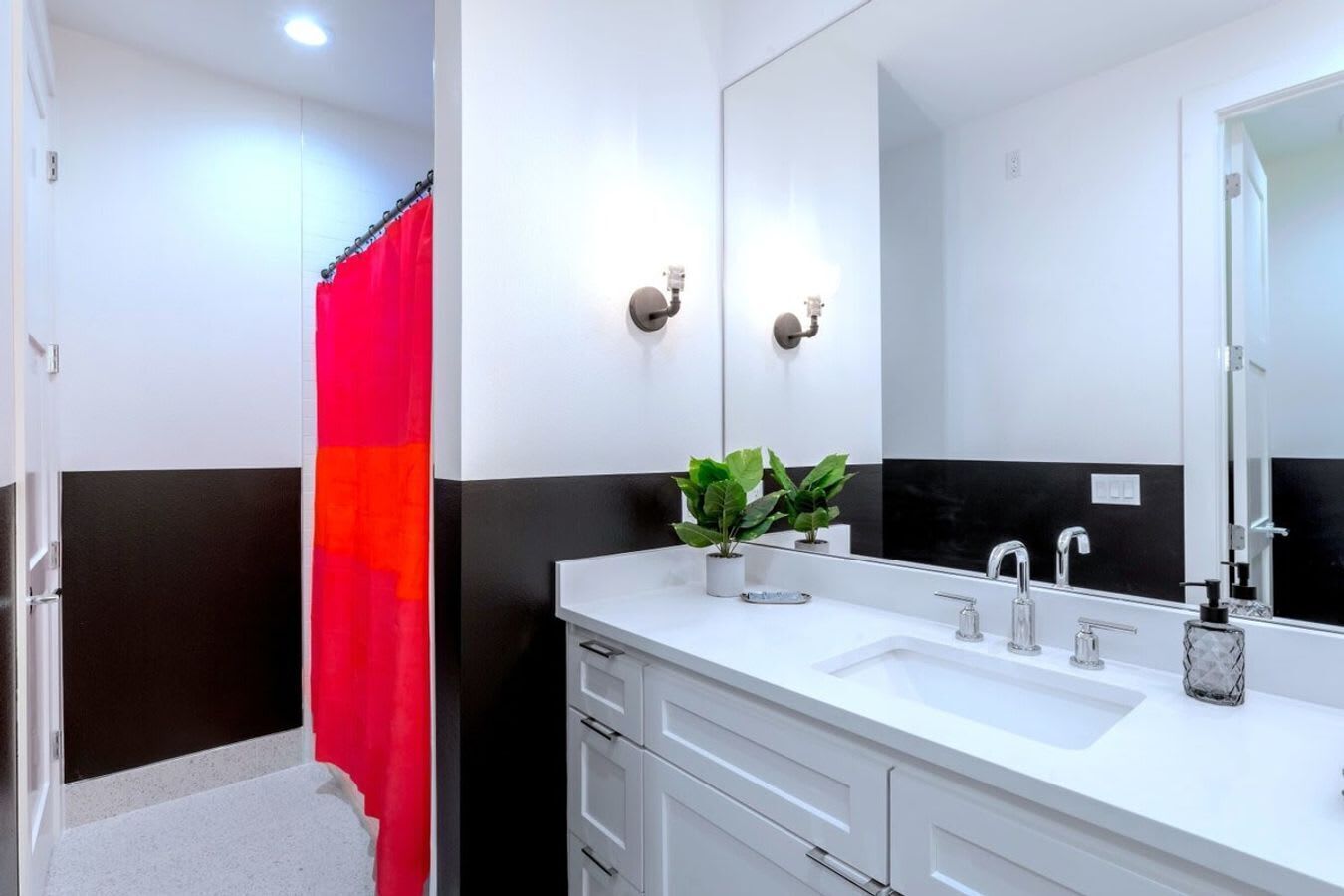 A modern bathroom with two sinks, a large mirror, and a shower curtain.