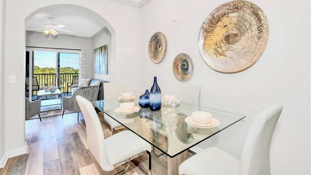 A modern dining area with a glass table, white chairs, and decorative plates.