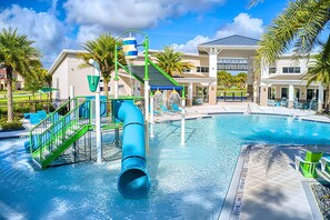 A swimming pool with a water slide, palm trees, and a building with a covered patio area. - Upstay Wonderful Resort Home w Patio & Pool Sleeps 26 (Kissimmee)