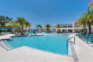 A swimming pool with a slide, palm trees, and lounge chairs. - Upstay Wonderful Resort Home w Patio & Pool Sleeps 26 (Kissimmee)