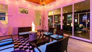 An outdoor seating area with wicker furniture, a fire pit, and string lights. - Mini Golf & Fireplace - East Austin Group Retreat (Austin)