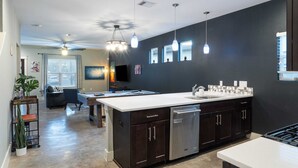 A modern kitchen with a central island, dark cabinetry, and pendant lighting. - Upstay Entertainment Hub w Games & Outdoor Firepit (Austin)