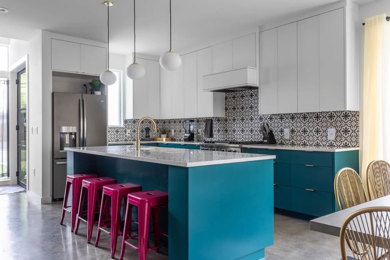 Una cocina moderna con una isla central, armarios blancos y un salpicadero con estampado.