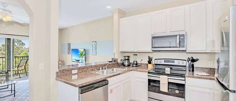 A modern kitchen with white cabinets, stainless steel appliances, and a granite countertop.