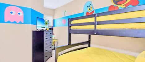 Un dormitorio infantil con literas, un televisor y decoración de pared con personajes de caricaturas.