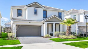Une maison à deux étages avec un garage, une pelouse bien entretenue et un palmier.